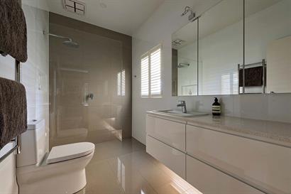 Subtle bathroom lighting mounted under floating high-gloss cabinets