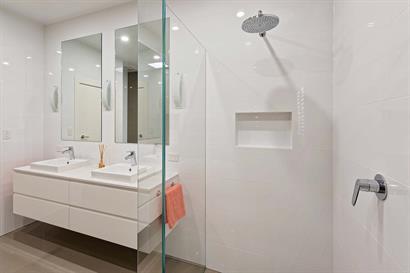 Double basins on floating cabinets and frameless shower with  wall inset