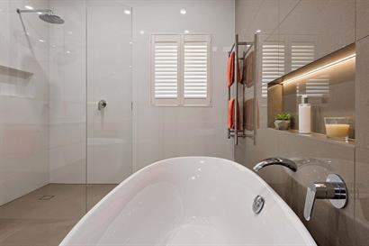 Freestanding oval bath and frameless corner shower with wall insets