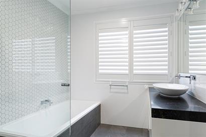 Small modern bathroom with plantation shutters, contemporary tiling and marble effect benchtop