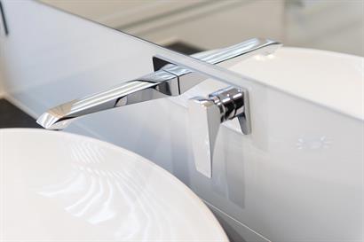 Contemporary bathroom mixer set mounted on seamless white glass splashback
