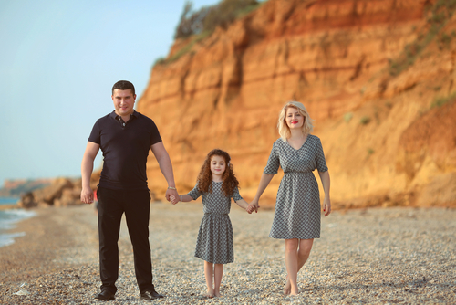 mom and dad walking on beach with childa