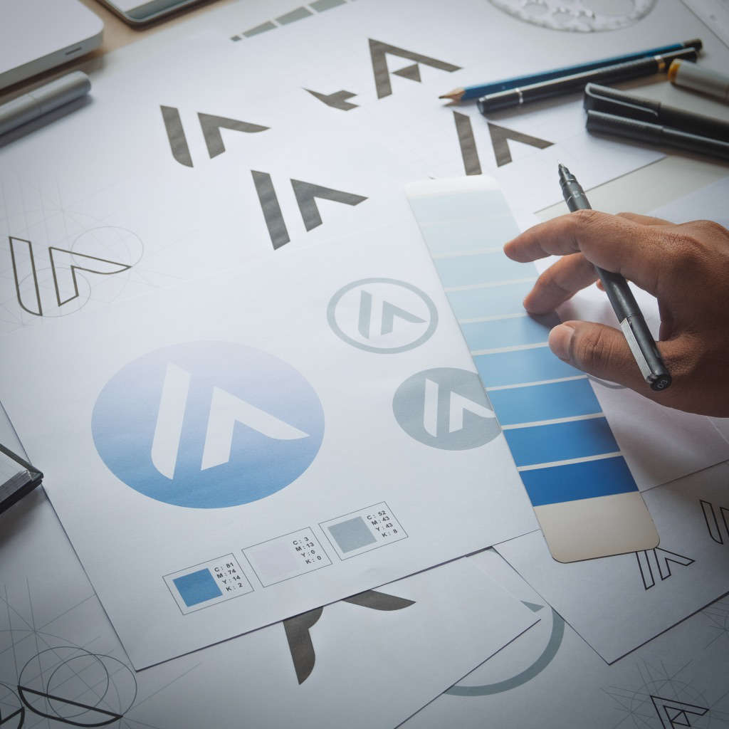man working on sketches of new logo and color swatches on desk
