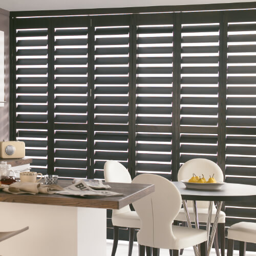 Full height charcoal shutters across a dining room window