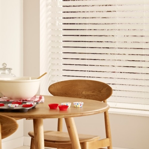 White faux wood Venetian blind with tapes in a dining room