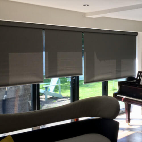 Grey motorised roller blinds over bi-fold doors