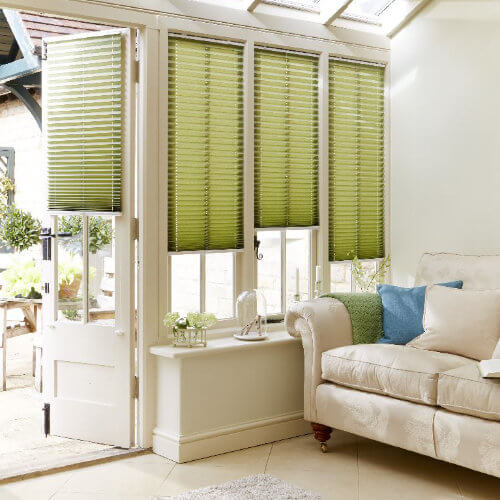 Green pleated blinds in a conservatory