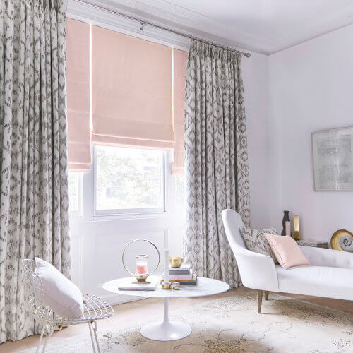 Pink roman blind with grey patterned curtains in a living room