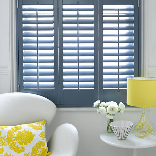 Blue grey plantation shutters in a bathroom bay window