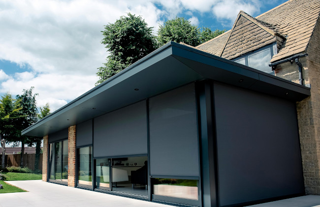 Grey external blinds on a flat roof extension seen from the garden