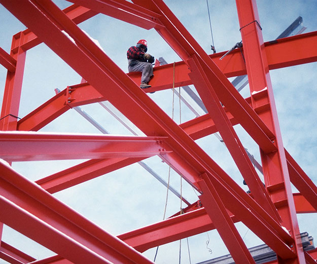 man sitting on red painted steel girders