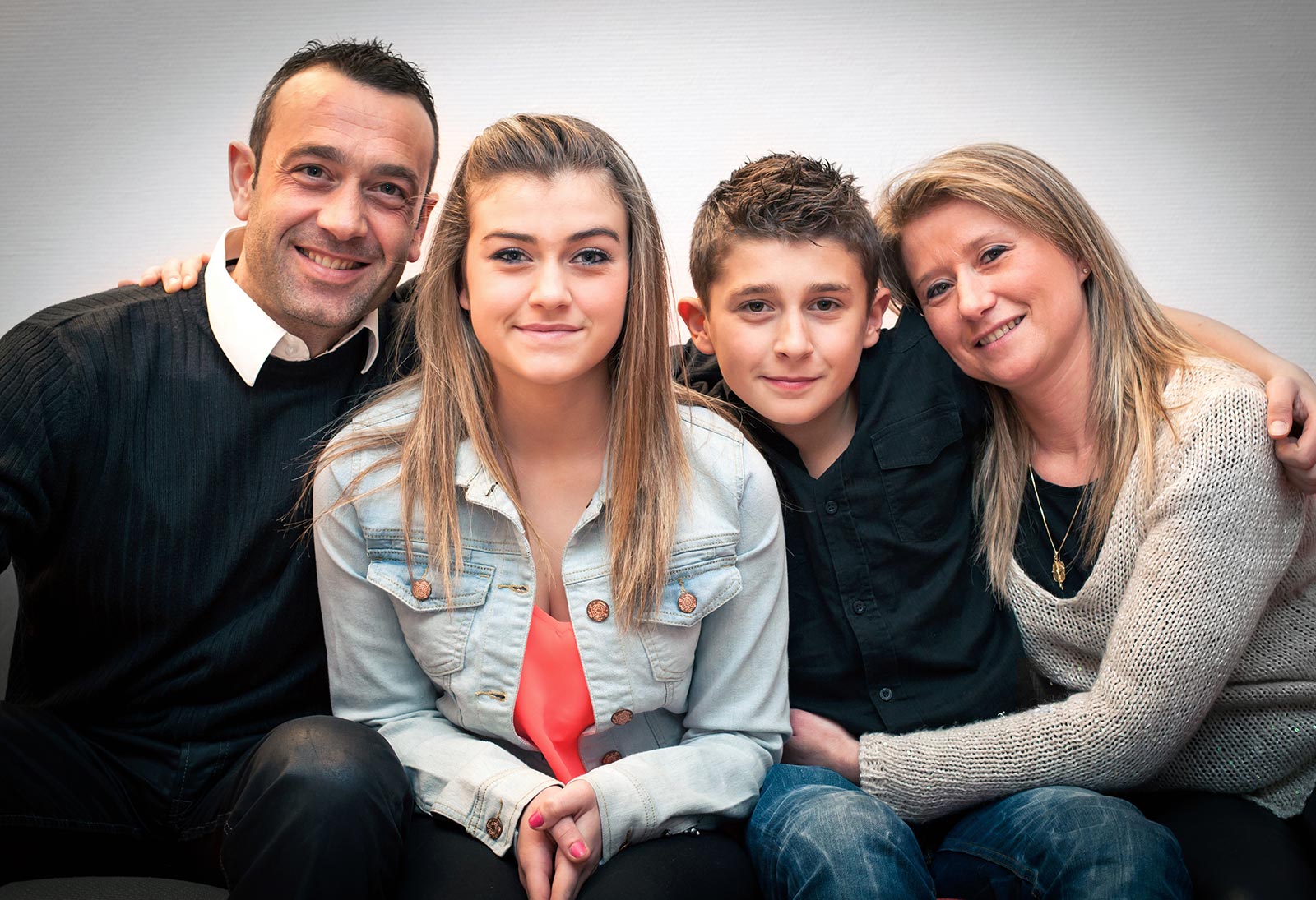 Portrait of seated family with a teenage girl and boy in the center