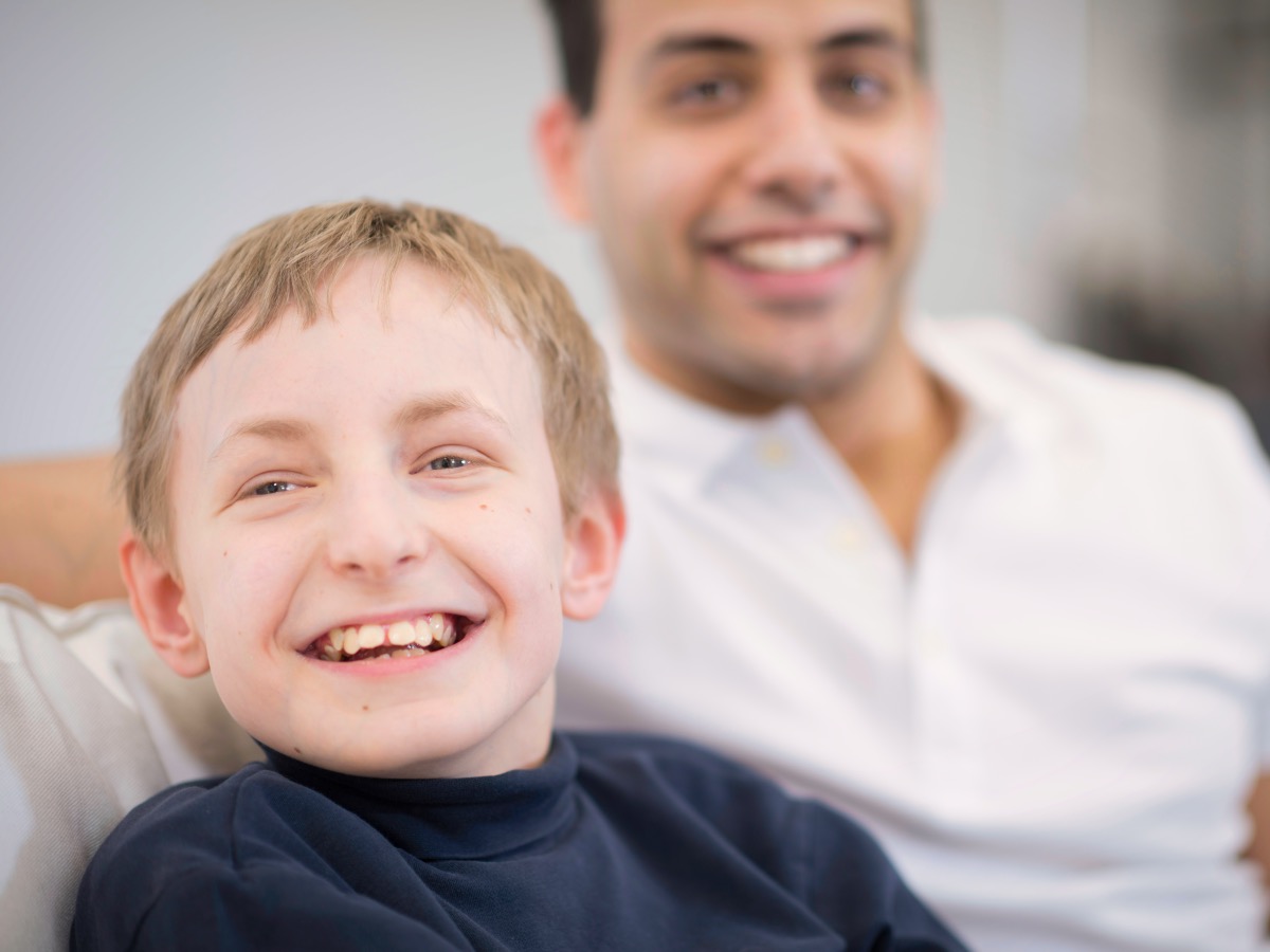 A happy child is sitting with his caregiver on a couch.