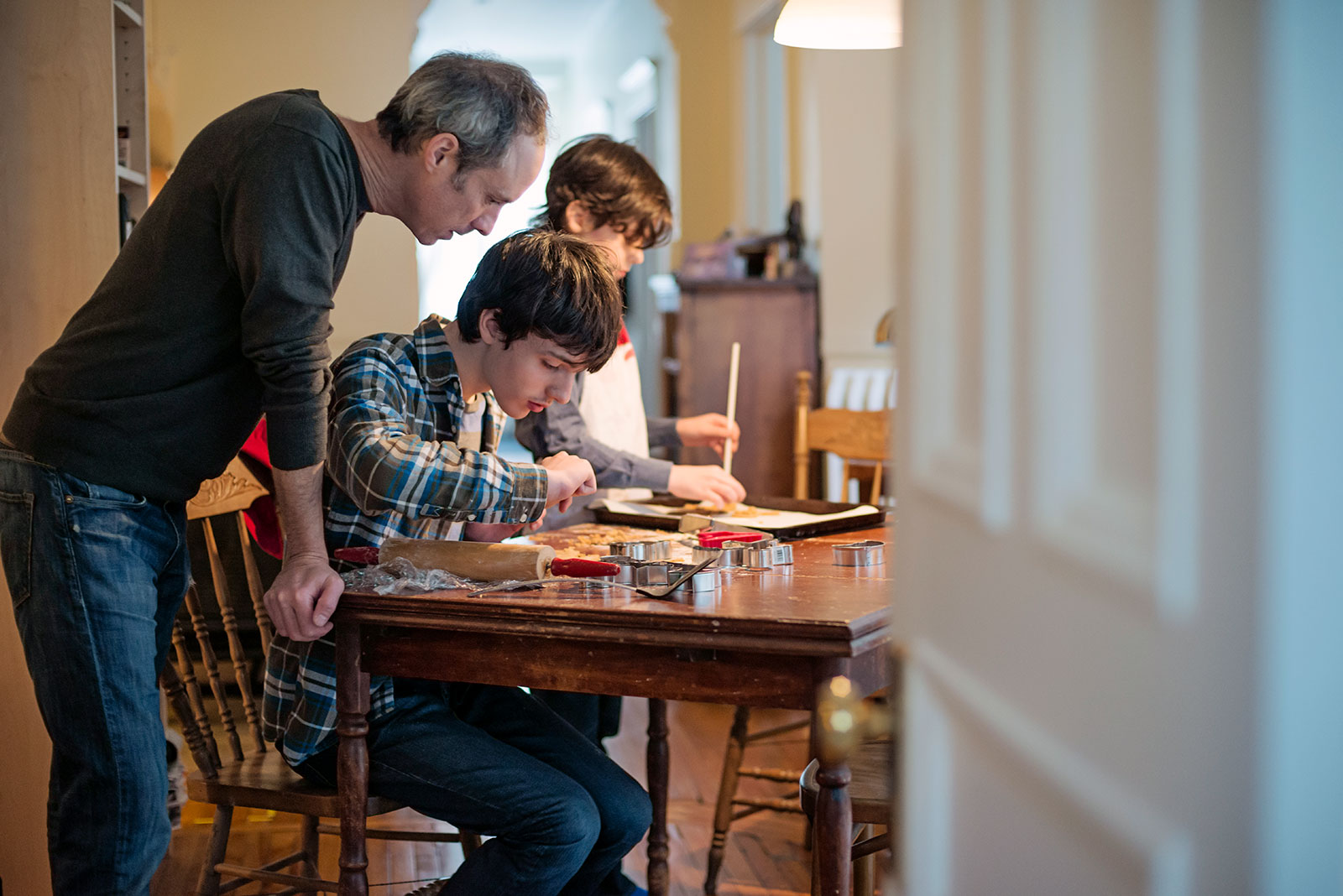 A father overseeing his two sons baking cookies