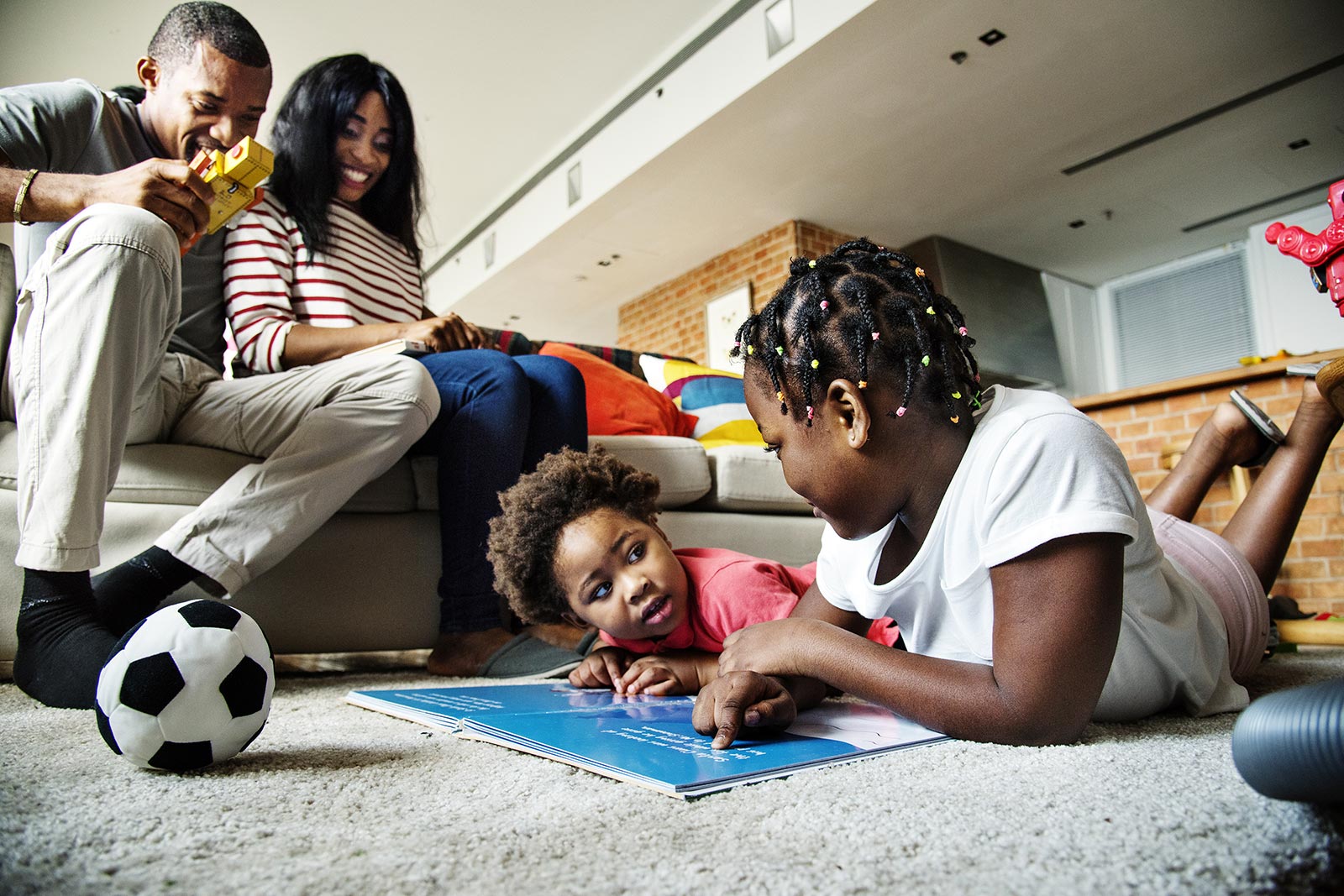 Young family at home with two young daughters playing together on the floor