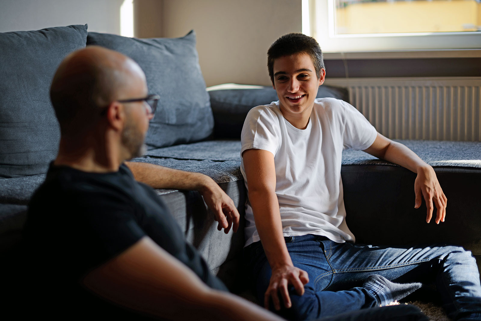 Teenage son enjoying a casual conversation with his father in their living room