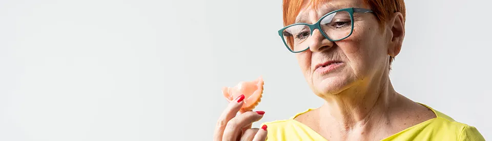 older woman looking at upper denture