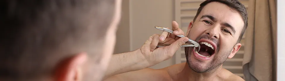 man attempting to pull his own tooth with pliers