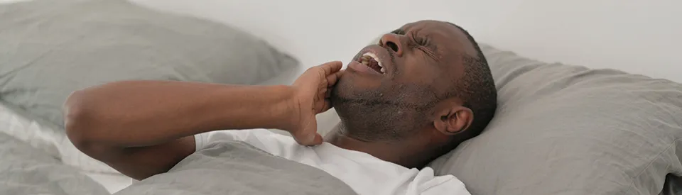 man in dental pain while laying in bed