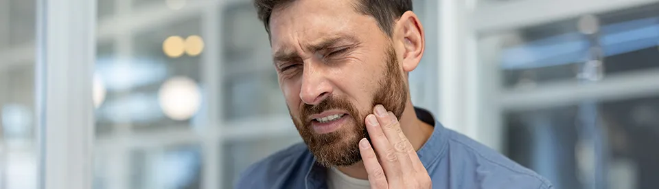 caucasian man holding jaw from tooth pain