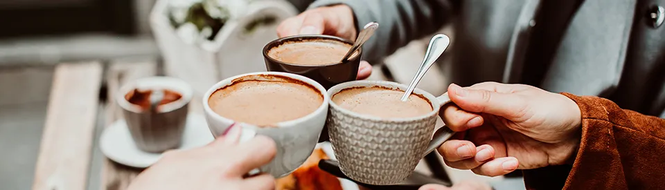 three coffee cups being held by their drinkers 