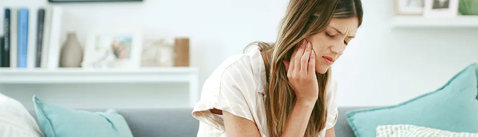 woman holding jaw in pain
