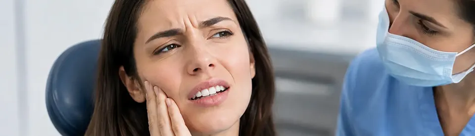woman holding her jaw in pain at dentist