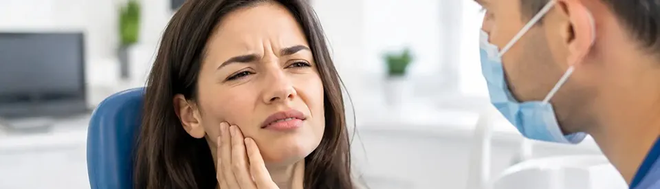 woman holding her jaw in pain at dentist