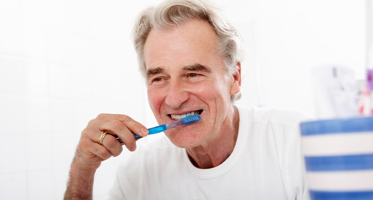 older man brushing teeth