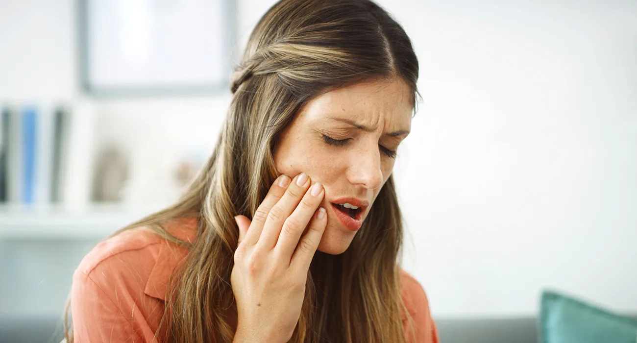 woman holding mouth in pain