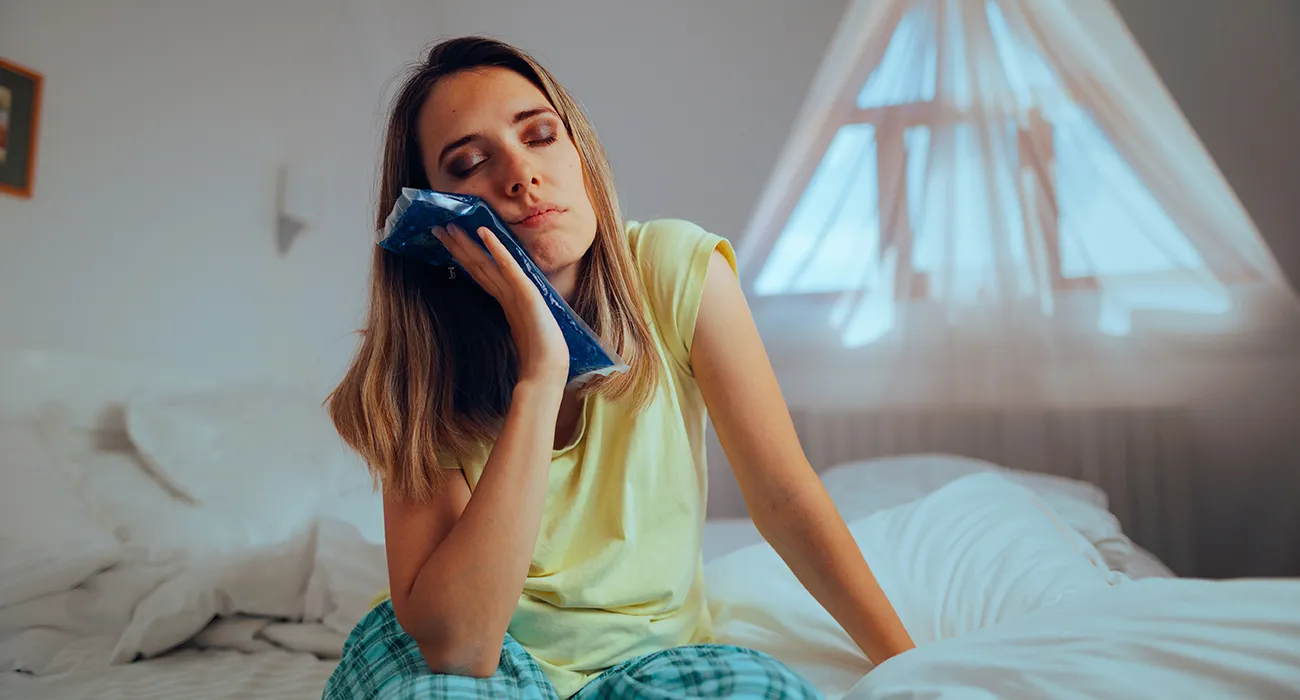 woman holding ice pack to her mouth