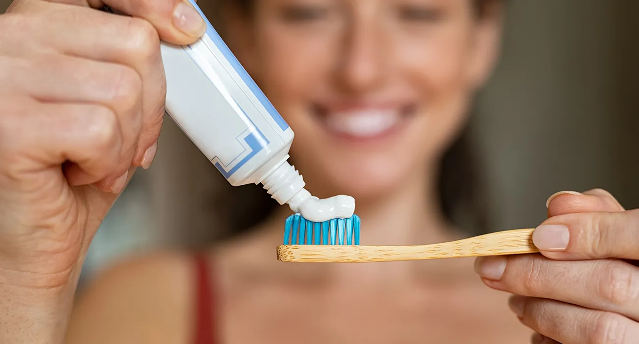 woman putting tothpaste on her toothbrush