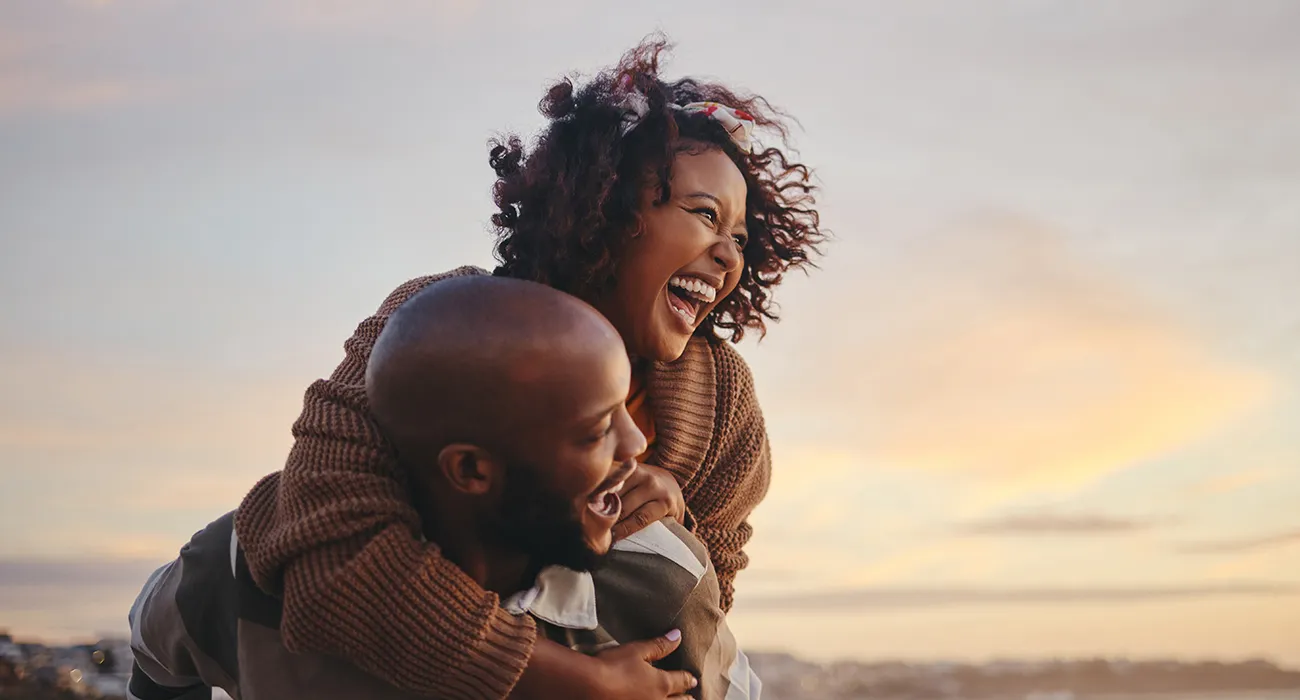black couple smiling and traveling piggy back