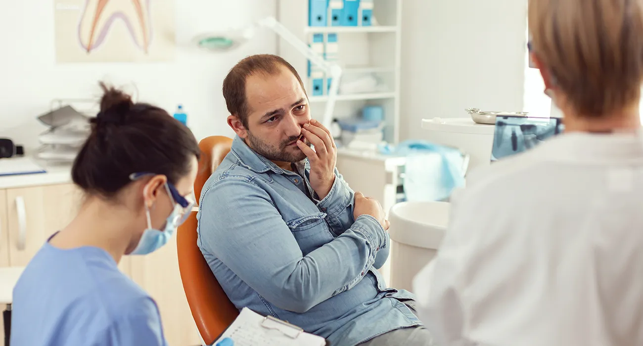 patient holding mouth in pain at dentist