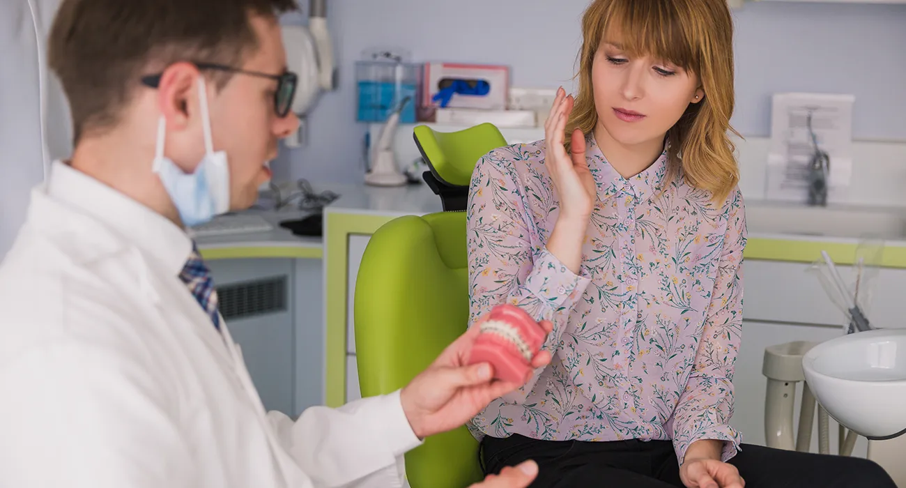 dentist consulting with patient who is holding their mouth in pain