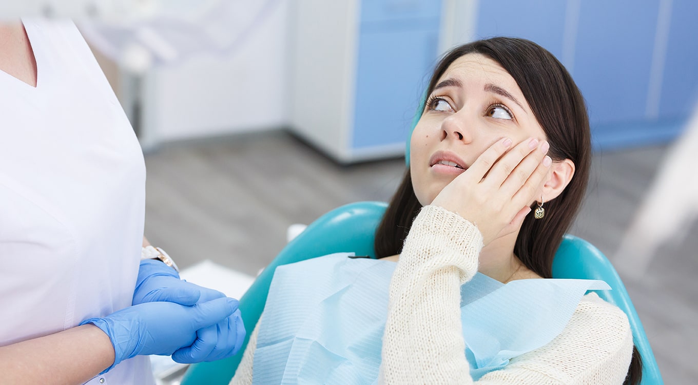 Emergency Dentist 24/7 San Diego, CA woman holding mouth in pain while at dentist