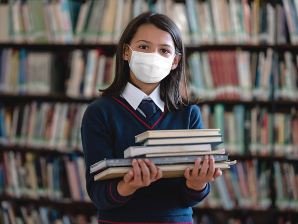 girl holding books at school wearing face mask