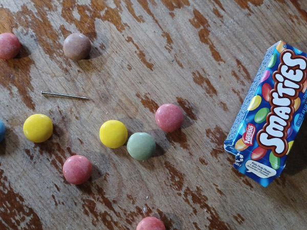 A box of open smarties with a pin found inside.