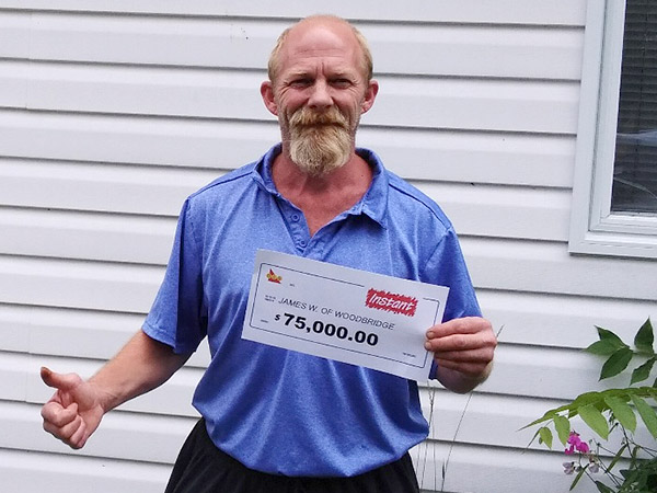 James Woodbridge stands outside with paper saying $75,000.