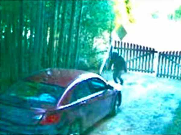 Security cam image of red car and person in front of car