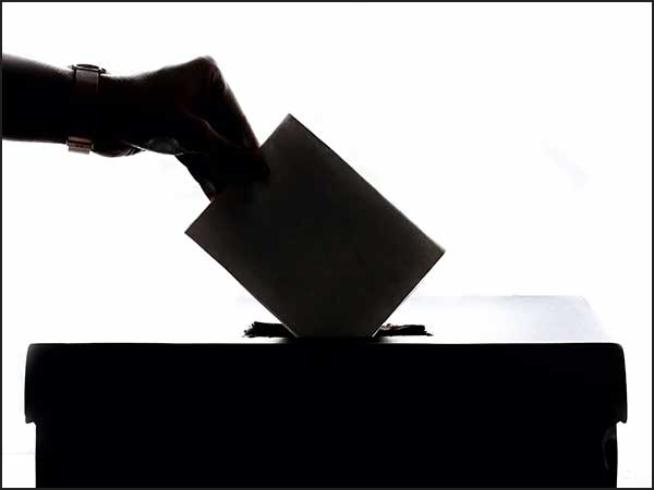 a hand putting ballot into ballot box
