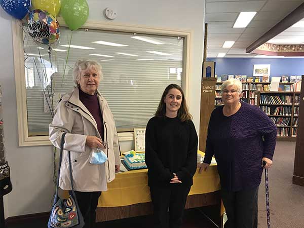 Markdale librarians pose in front of cake celebrating 125th anniversary
