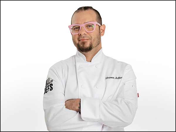Shawn Adler posing in a Wall of Chefs uniform