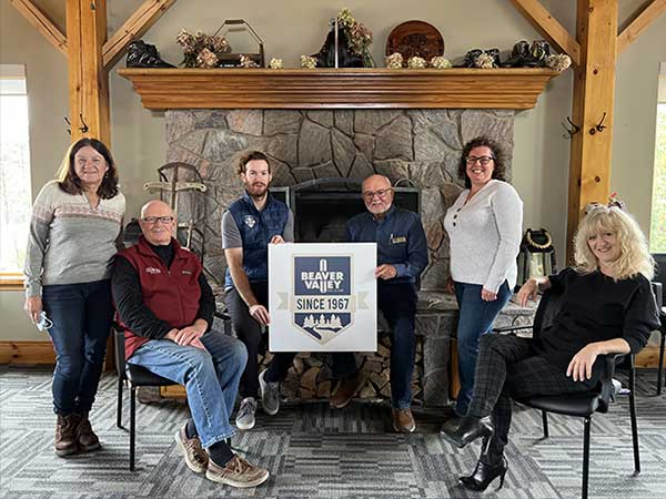 Beaver Valley Ski Club members sitting in lounge holding logo sign