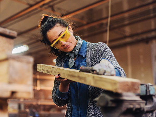 woman in construction gear holding a 2x4