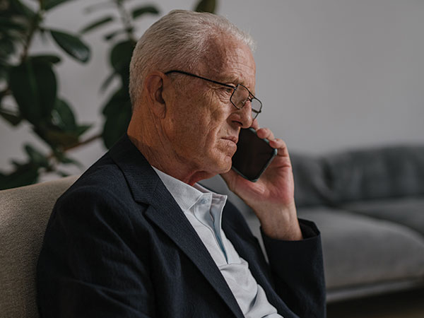 older man speaking on phone looking serious.