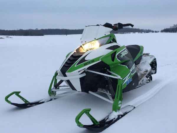 Green and white arctic cat snowmobile