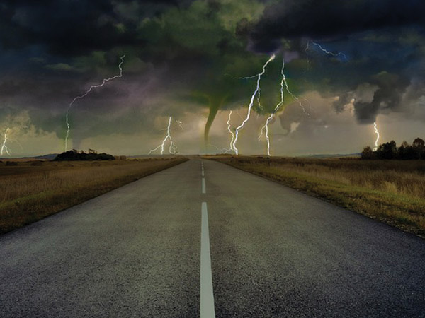 Dark clouds, lightning and tornado ahead on highway.
