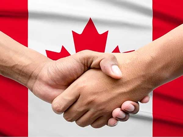 hands shaking in front of a Canadian flag