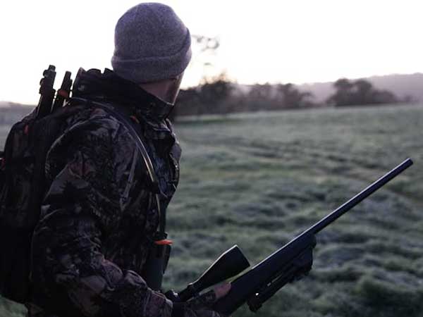 Hunter with rifle looking out over a field